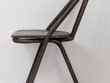 the chair is made of metal and has a black leather seat