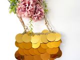 a gold purse hanging on a white wall with flowers