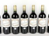 six bouteilles de vin sont alignées sur une surface blanche