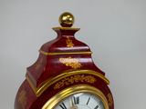 a red and gold clock sitting on a table