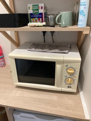 a microwave sitting on top of a wooden shelf next to a microwave oven