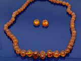 une photo d'un ensemble composé d'un collier et de boucles d'oreilles, posée sur un fond bleu