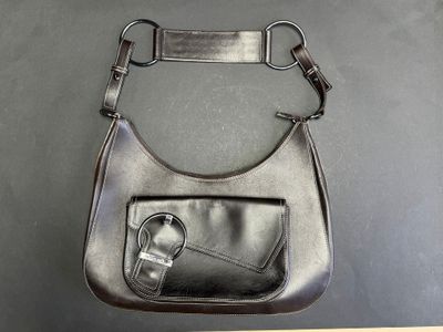 black leather purse with a metal handle on a black surface