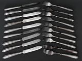 a lot of forks and knives on a black table