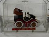 a small model of an old car in a glass case