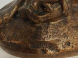 bronze statue of a dog sitting on a rock with its head resting on the ground