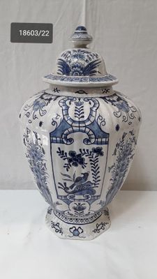 a blue and white vase with a lid on a table
