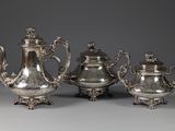 trois théières en argent et une cafetière sur une table