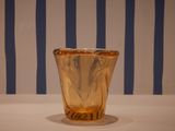 a glass vase sitting on a table with a striped wall behind it