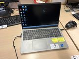 un ordinateur portable posé sur un bureau, à côté d'un clavier