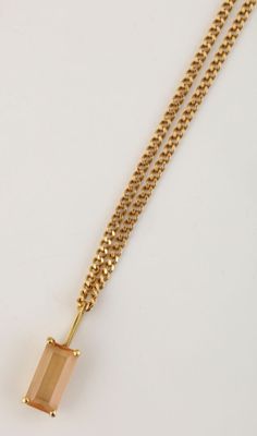 un collier en or avec un pendentif en forme de carré orné d'une pierre, monté sur une chaîne