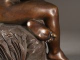 a bronze statue of a woman sitting on a rock