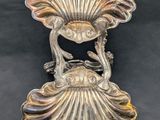 a silver plate with a bird on it on a black background