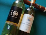 deux bouteilles de vin et un cigare posés sur une table de billard