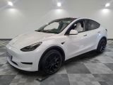 un SUV Tesla blanc garé sur un sol à damier dans un garage
