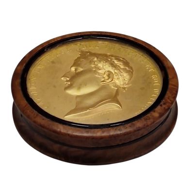 a gold coin in a wooden box on a white background