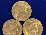 three gold sovereigns sitting on top of each other on a blue surface