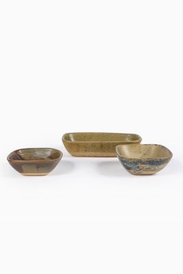 trois petits bols et un grand bol sont posés sur une surface blanche