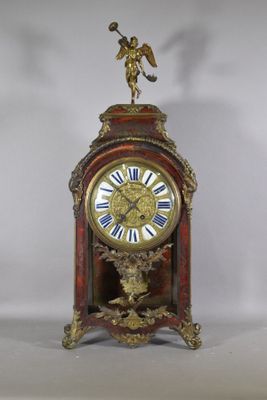 a clock that is sitting on a table with a statue on top of it