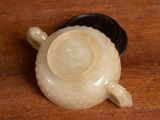 a small white tea pot sitting on a wooden table