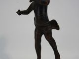 une statue en bronze représentant un garçon tenant une raquette de tennis