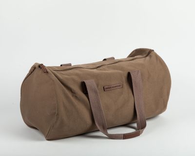 un sac de voyage marron posé sur une surface blanche