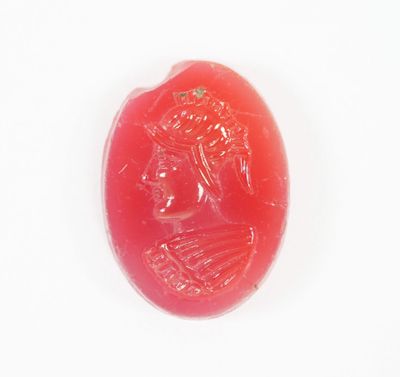 une image représentant un bouton en jade rouge orné du visage d'une femme