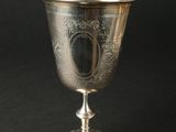 une coupe ancienne en argent posée sur un socle, sur fond noir