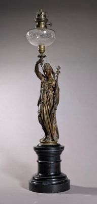 une statue représentant une femme tenant une lampe posée sur une table