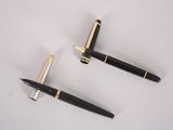 two pens sitting next to each other on a white surface