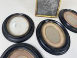 four black and gold oval picture frames with a chalk board in the background