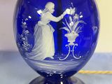 a blue glass vase with a picture of a woman on it