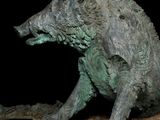 a statue of a boar that is sitting on a piece of wood