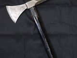 a close up of a large metal axe on a black cloth