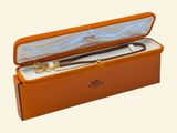 une boîte orange contenant un stylo, sur fond blanc