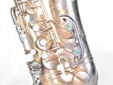 a silver saxophone that is sitting on a clear stand
