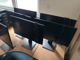 three computer monitors sitting on top of a wooden desk