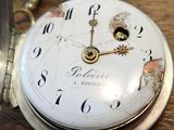 a close up of a pocket watch on a wooden table