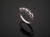 a white gold ring with blue sapphires and diamonds on a black surface