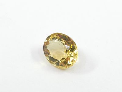 a yellow sapphire stone on a white surface