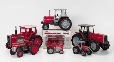 three toy tractors are sitting next to each other on a white surface