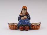 une petite figurine de femme assise sur un bateau