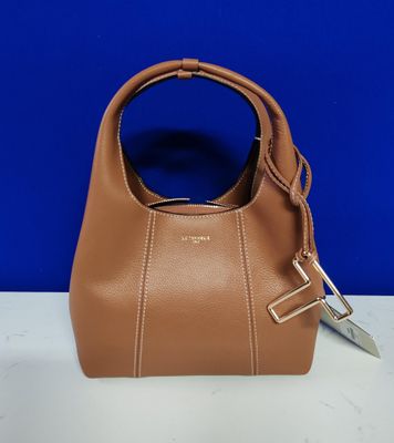 un sac à main marron muni d'une poignée en métal, posé sur une table blanche