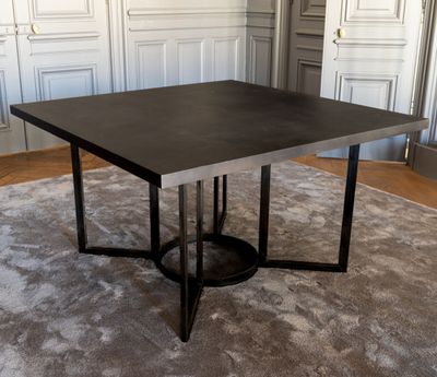 La table est en métal et possède un plateau noir.