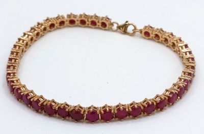 a close up of a bracelet with red stones on a white surface