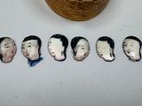 five ceramic heads of people on a table next to a bowl
