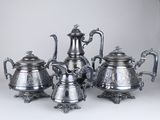four pieces of silver tea and coffee set on a white surface