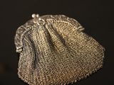 a close up of a silver purse on a black surface