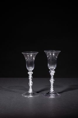 two empty wine glasses sitting on a table with a black background