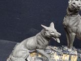 statue of two dogs sitting on a marble base on a black background